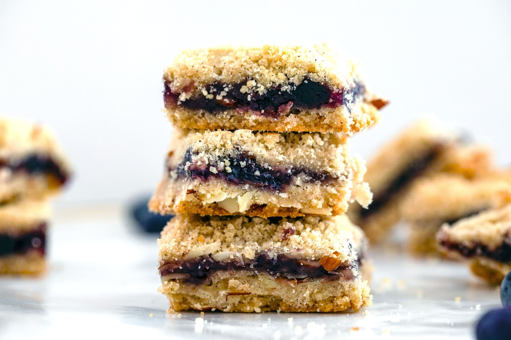 Head-on landscape view of a stack of almond blueberry bars with more in background.