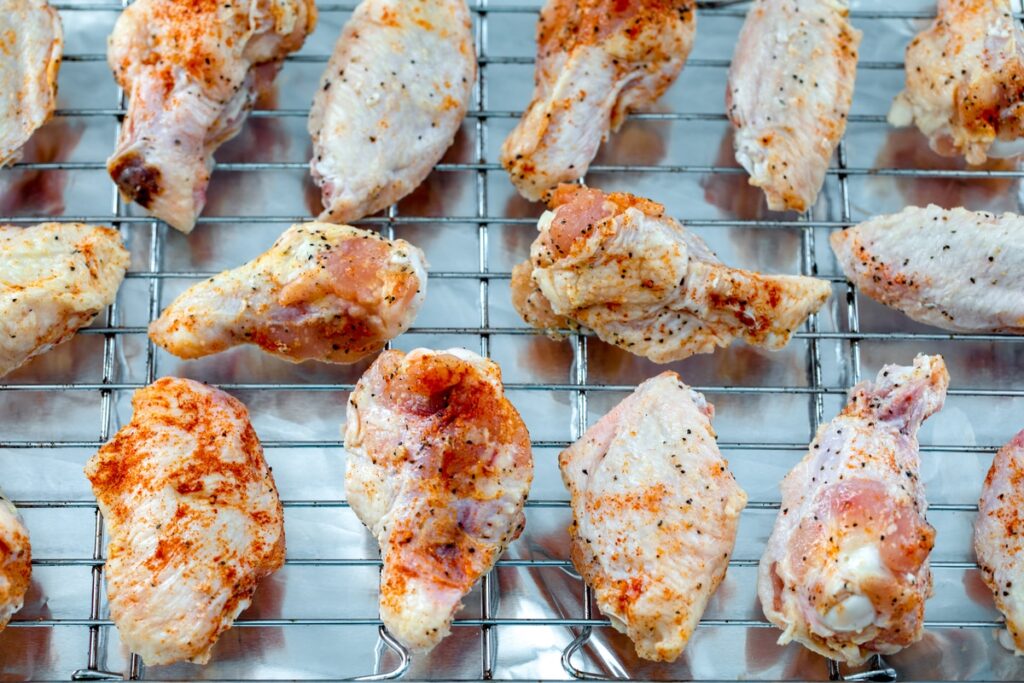 Wings laid out on baking rack over foil-covered baking sheet