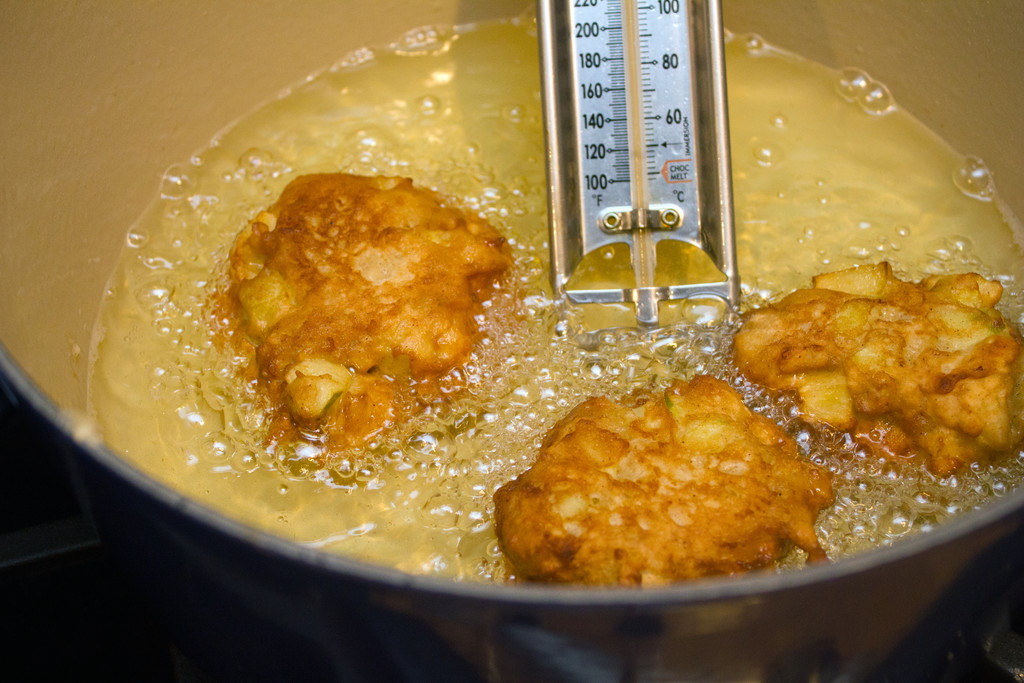 Apple Fritters Frying in a dutch oven filled with oil with a thermometer in it