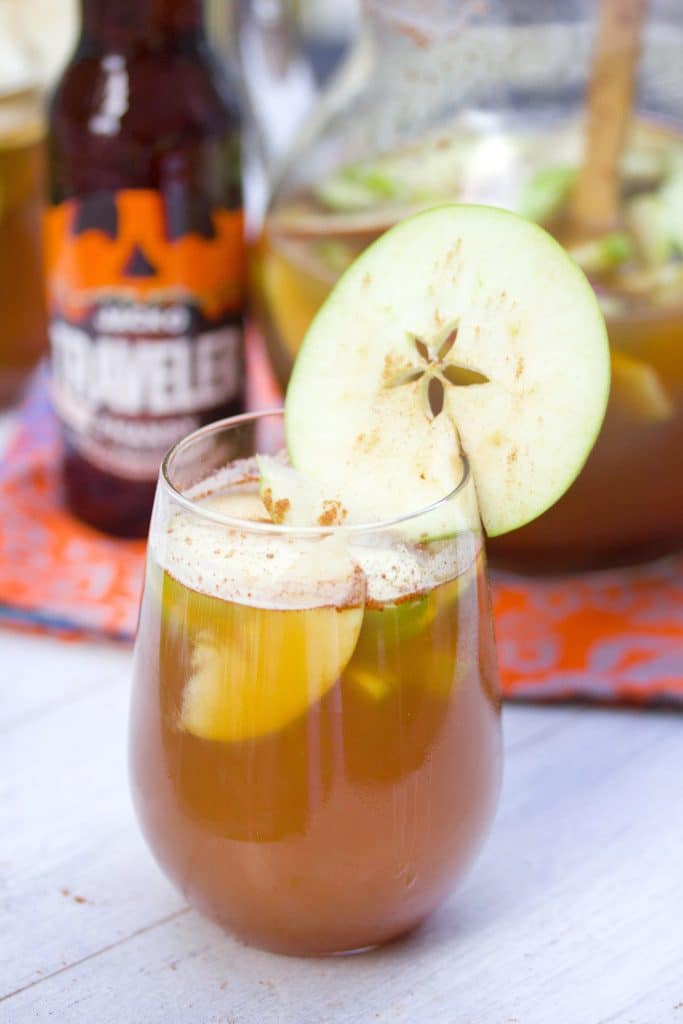 Closeup head-on view of a glass of apple pumpkin shandy sangria with an apple ring garnish