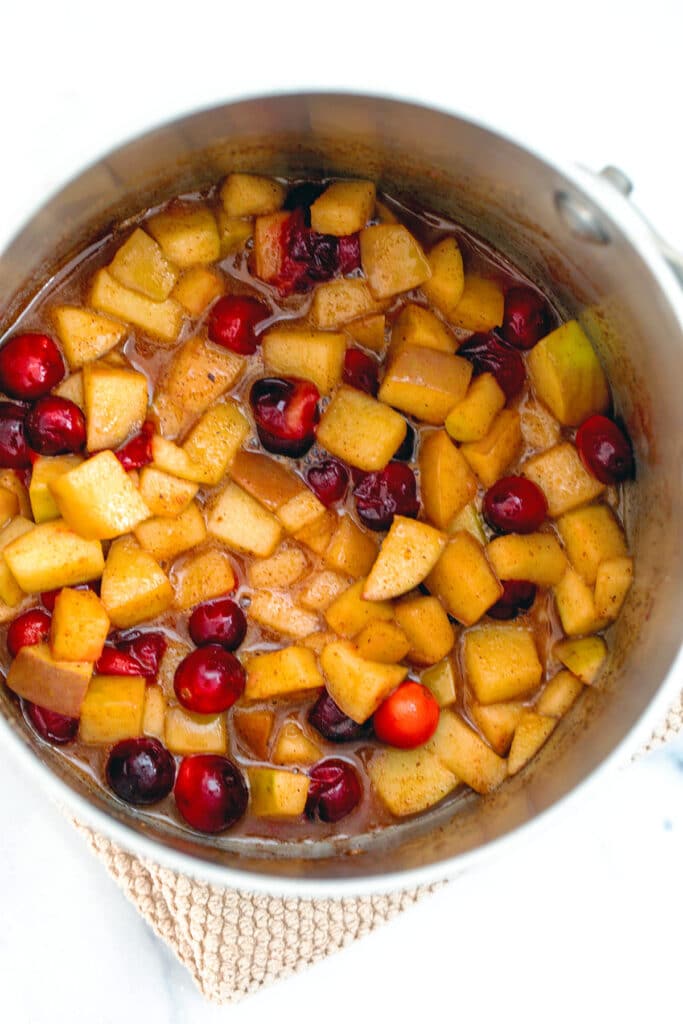 Overhead view of cranberries and chopped apples cooked in saucepan
