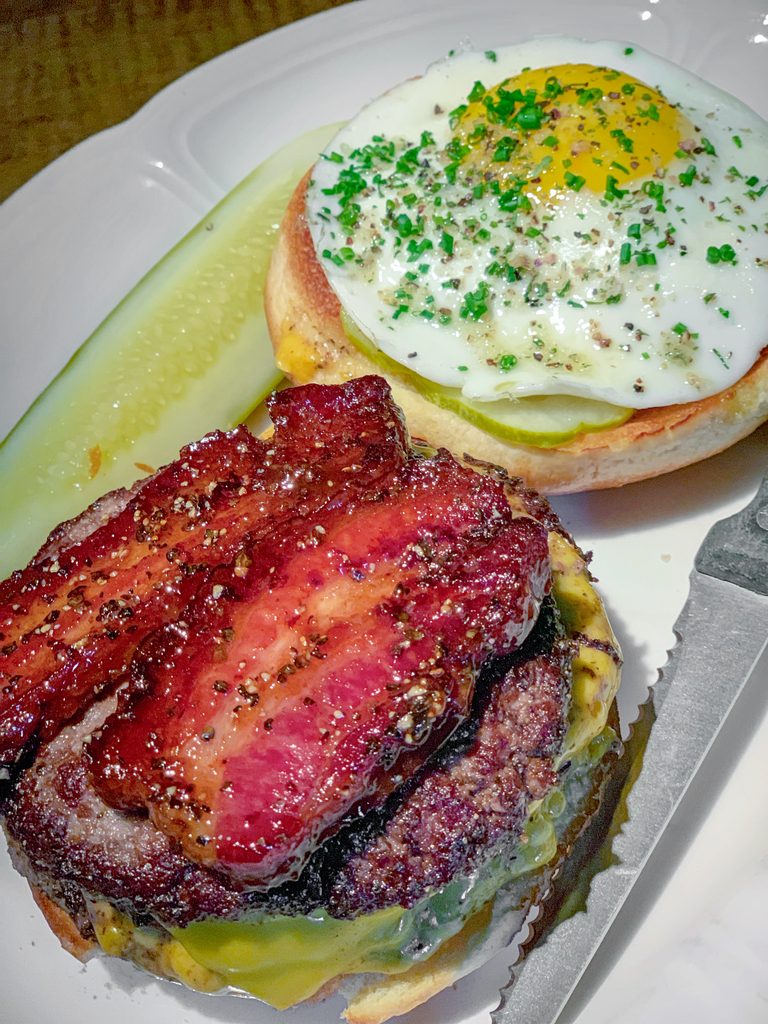 Overhead view of Au Cheval's cheeseburger with thick-cut bacon and sunnyside up egg