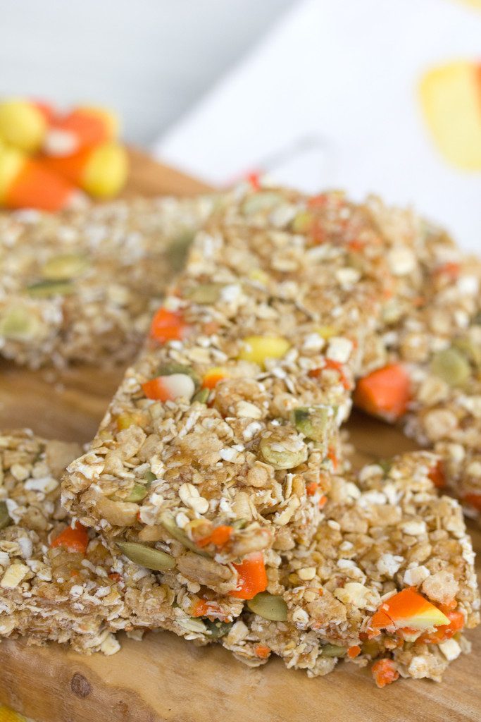 Head-on close up view of candy corn granola bars on a wooden board