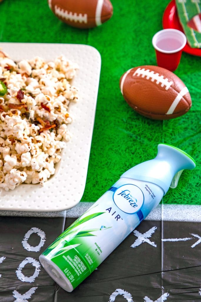 Overhead view of Febreze AIR, platter of jalapeño cheddar popcorn, mini footballs, and cups on a football field tablecloth