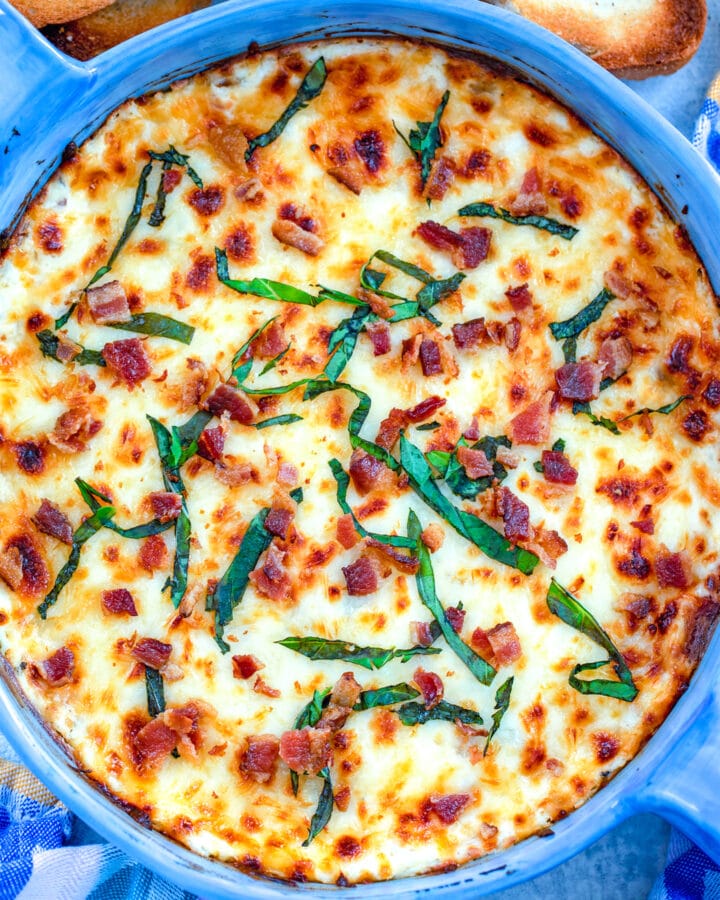 Bacon white pizza dip topped with crumbled bacon and basil