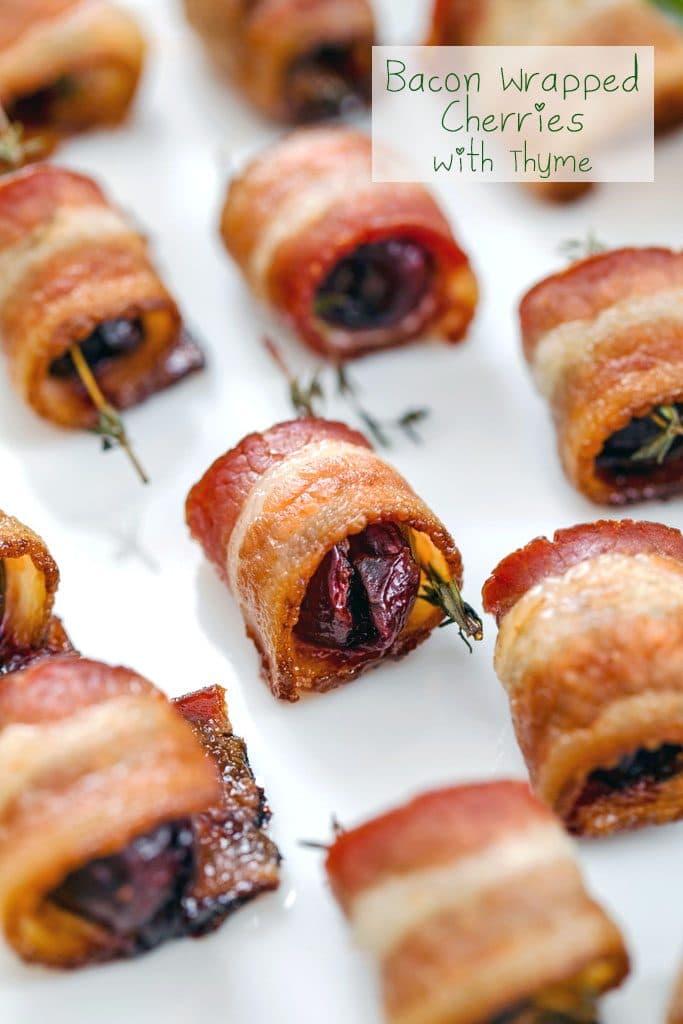 Close-up of platter of bacon wrapped cherries with thyme on white plate with "Bacon Wrapped Cherries with Thyme" text at top