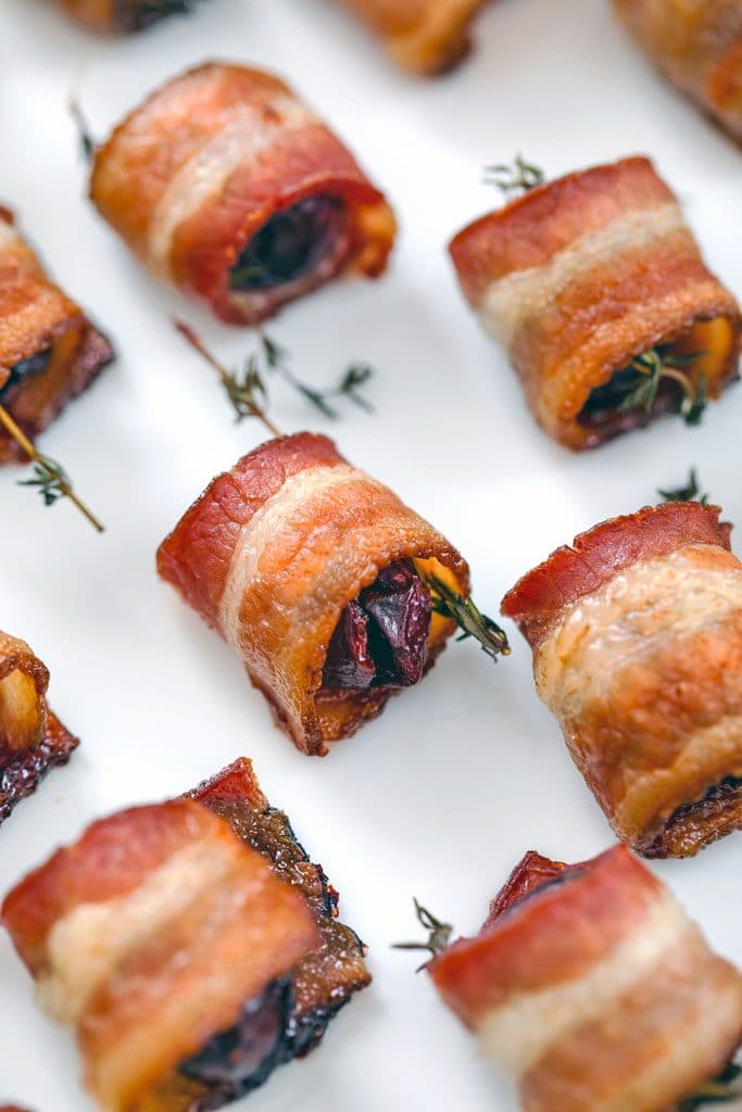 Close-up of bacon wrapped cherries with thyme after baking on white plate