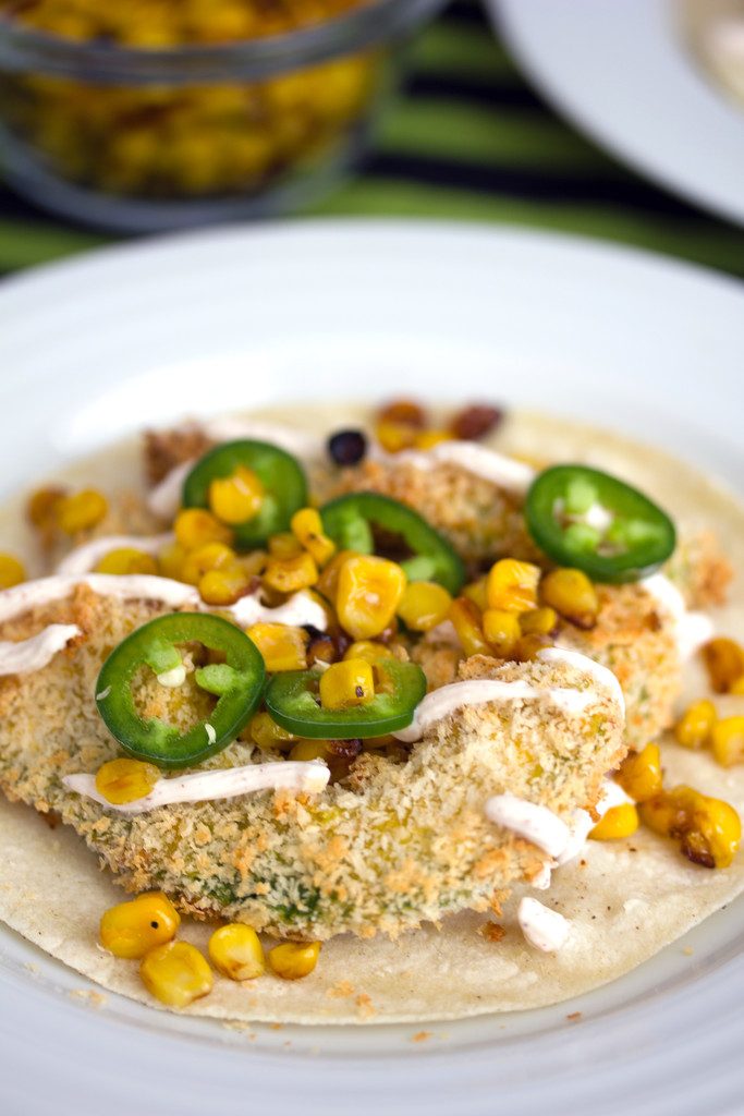 Head-on closeup of baked avocado taco with sliced jalapeño, grilled corn, and Greek yogurt sauce