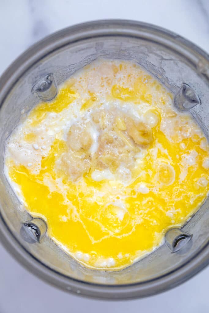 Overhead view of milk, eggs, mashed banana, flour, and sugar in blender