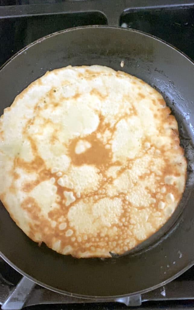 Crepe cooking and turning golden in pan
