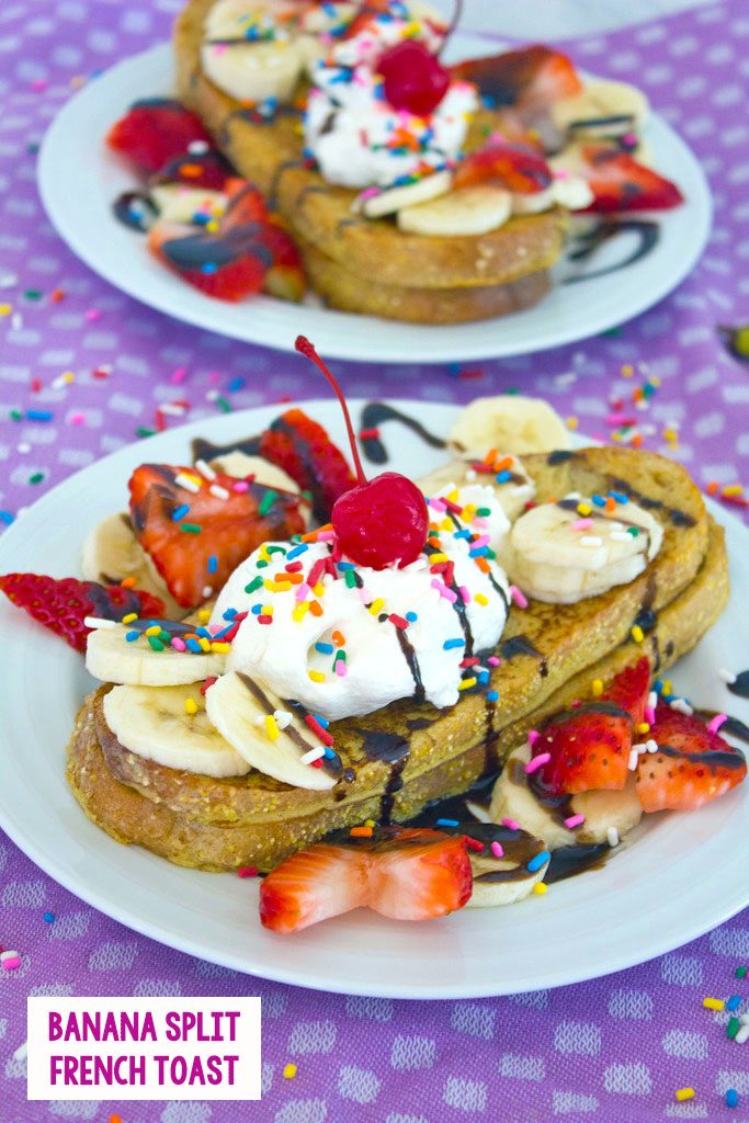 Head on view of a white plate with banana split french toast topped with bananas, strawberries, whipped cream, chocolate, sprinkles, and a cherry with a second plate in background and recipe title at bottom