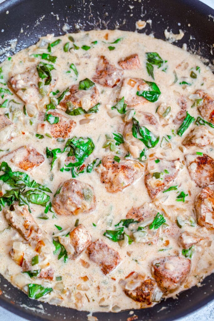 Overhead view of coconut curry sauce with chicken and basil cooking in it