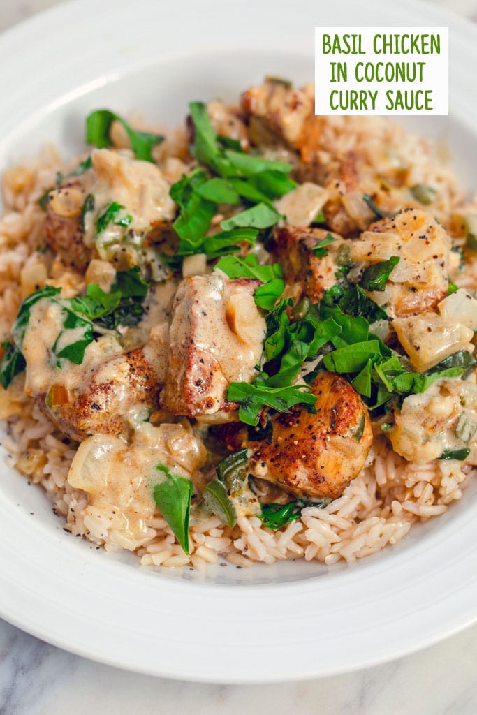 Overhead closeup view of a white bowl filled with brown rice and topped with basil chicken in coconut curry sauce with extra fresh basil on top and recipe title at top of image