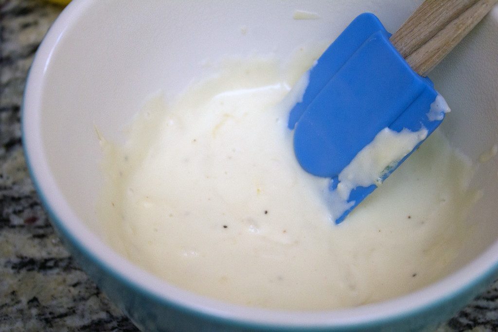 Overhead view of bowl of mornay sauce with spatula stirring