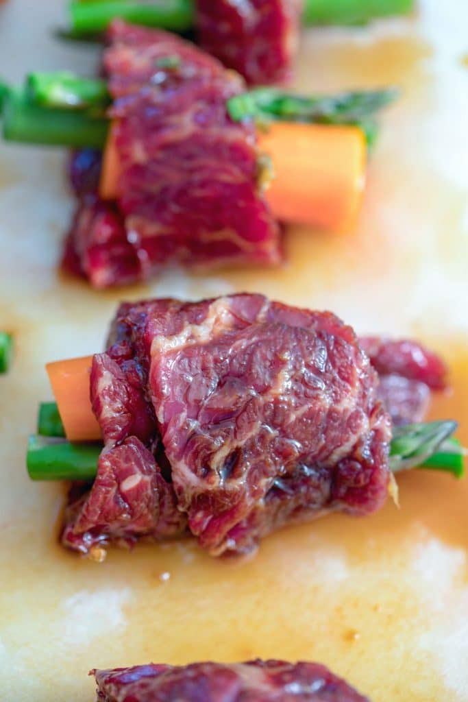 Overhead view of raw steak wrapped around asparagus and carrot