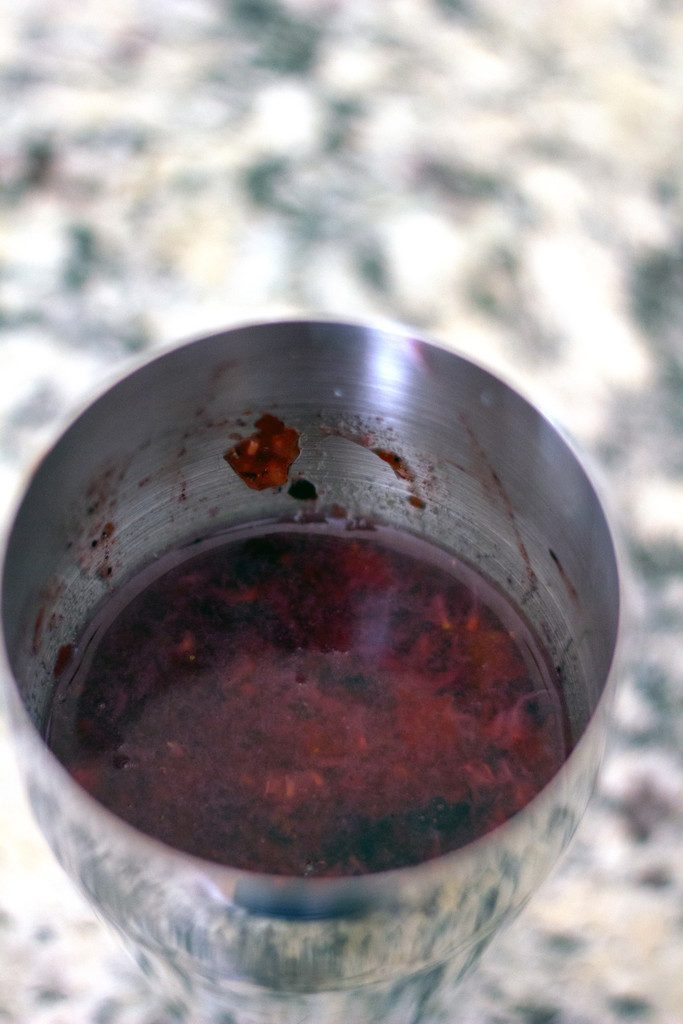 An arial view of a cocktail shaker with berries smashed with gin