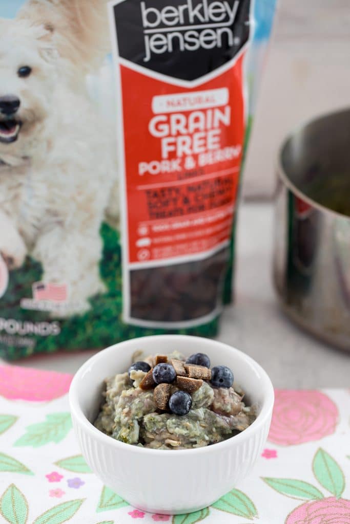 Shot of berry egg oatmeal for dogs in a white bowl with Pork and Berry Link treats in the background 