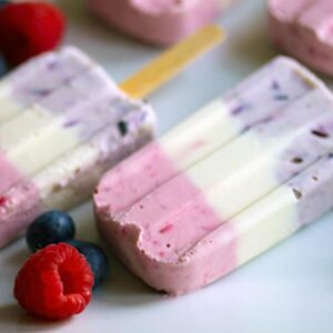 Berry Greek Cheesecake Popsicles -- These popsicles combine fresh berries with Greek cream cheese for a healthy pastel red, white, and blue frozen treat! | wearenotmartha.com
