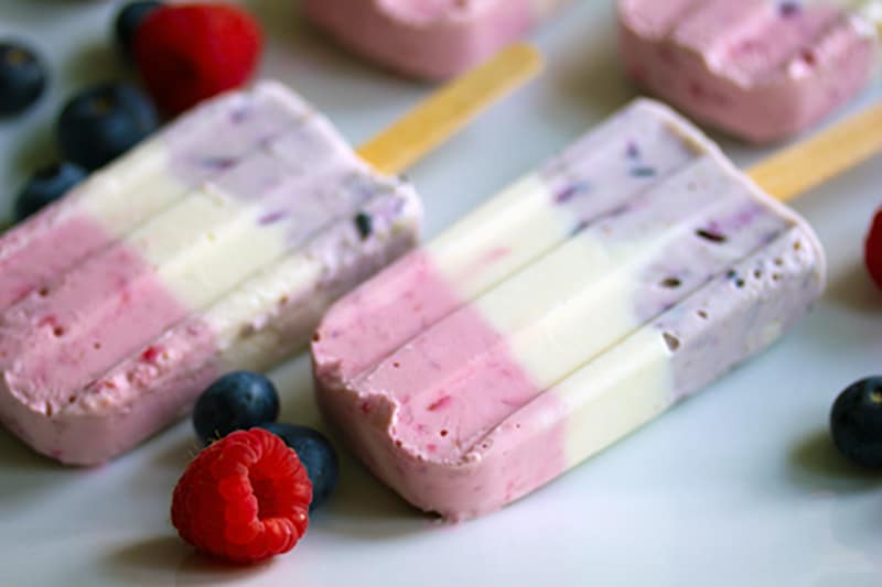 Overhead closeup view of Berry Greek Cheesecake Popsicles showing red, white, and blue layers