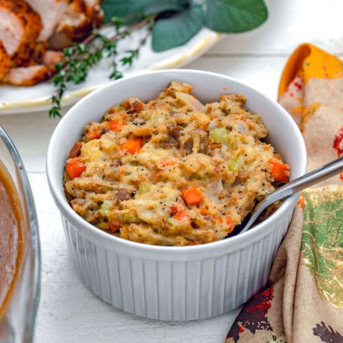 Head-on view of Thanksgiving stuffing in small casserole dish with turkey platter in background