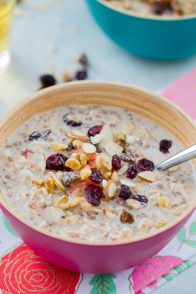 Head-on closeup view of a pink bowl of bircher muesli topped with dried fruit and nuts