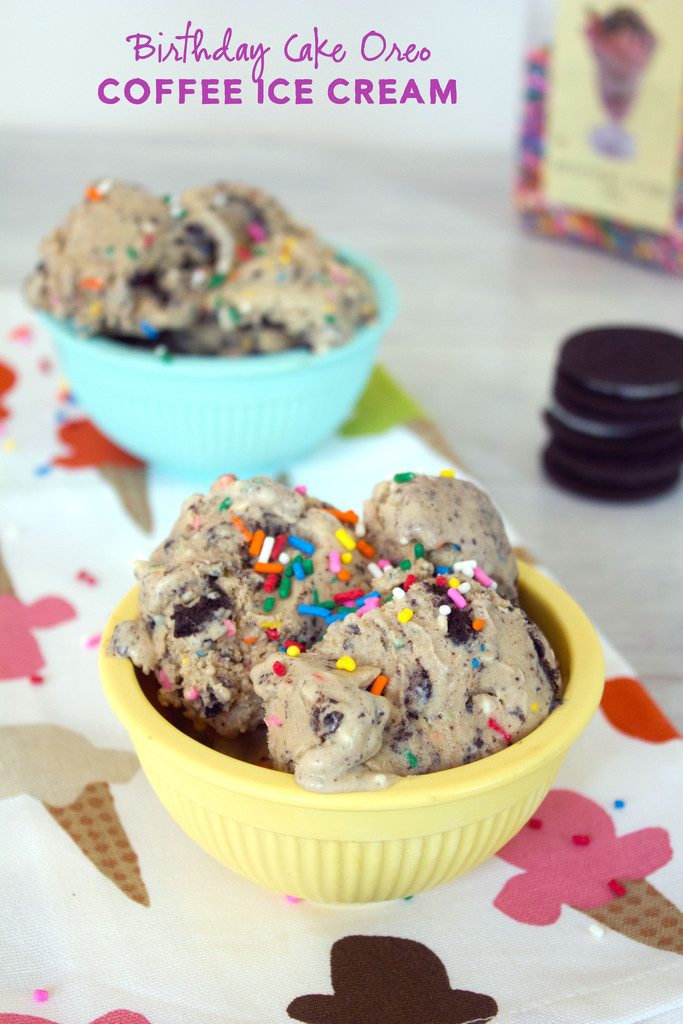 Head-on view of a yellow bowl of coffee birthday cake ice cream with birthday cake Oreos and rainbow sprinkles on a ice cream-themed tea towel with a second bowl of ice cream, Oreo cookie stack, and sprinkles in the background and recipe title at top