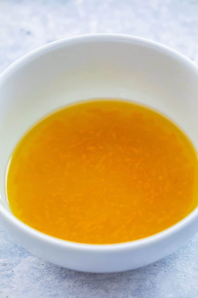 Head-on view of white bowl with lemon honey salad dressing on grey surface