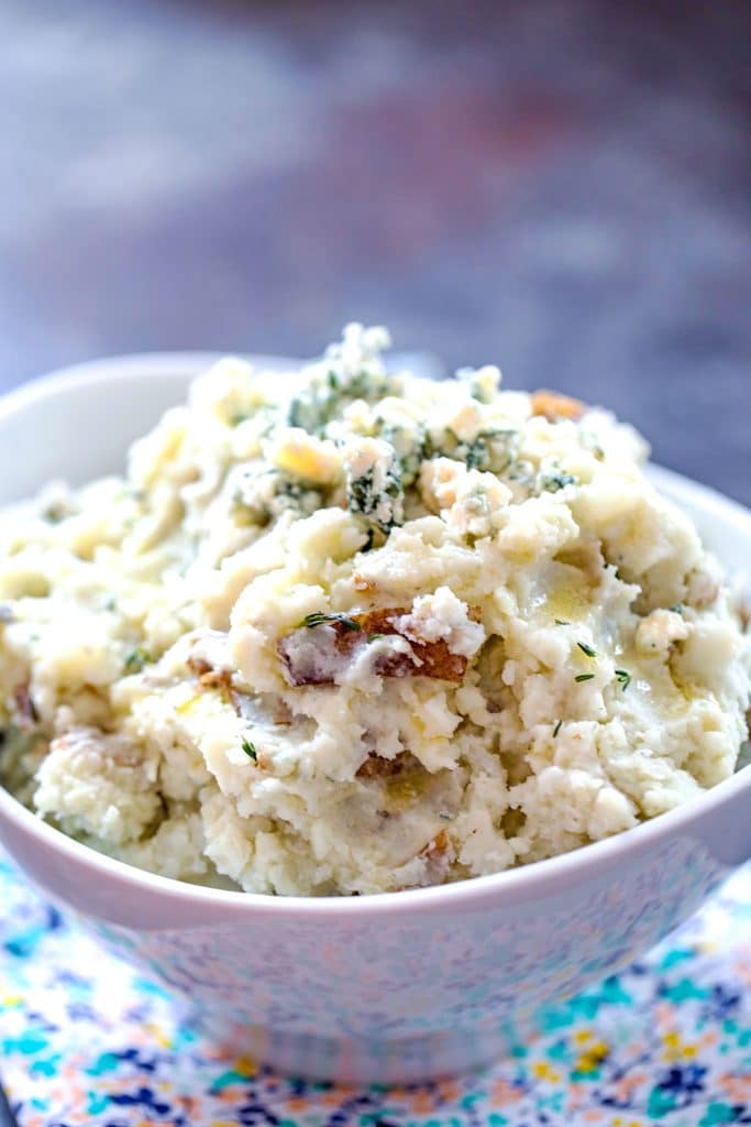 Overhead view of a white serving bowl of blue cheese mashed potatoes with rosemary