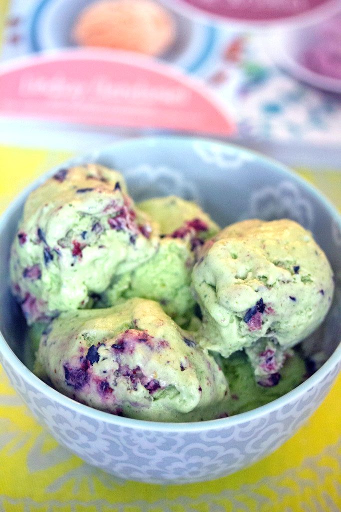 Overhead view of green blueberry kale ice cream in a bowl with cookbook in the background