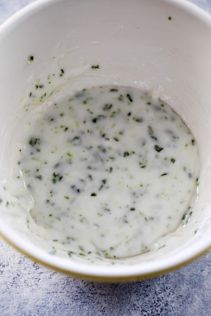 Overhead view of mint lime icing in a bowl with lots of finely chopped mint