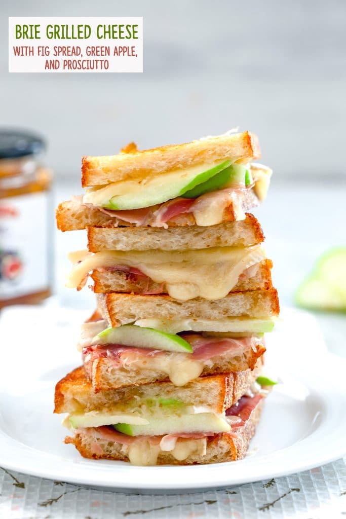 Four halves of a brie grilled cheese sandwich with fig spread, green apple, and prosciutto all stacked on each other on a white plate with recipe title at the top of the photo