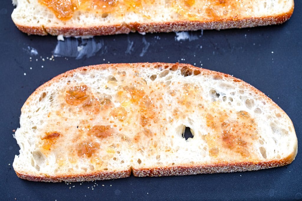 Slice of scala bread slathered with fig spread on a griddle