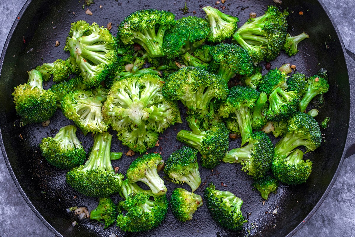 Overhead view of broccoli and garlic cooking in skillet.