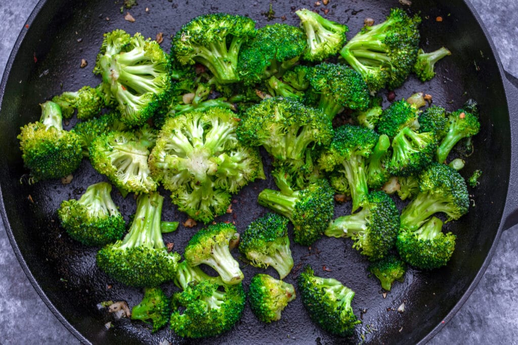 Overhead view of broccoli and garlic cooking in skillet