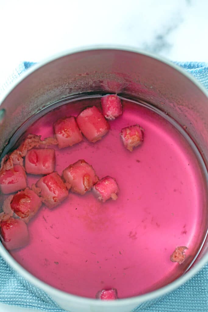 Overhead view of saucepan with pink simple syrup simmering with bubblegum in it.