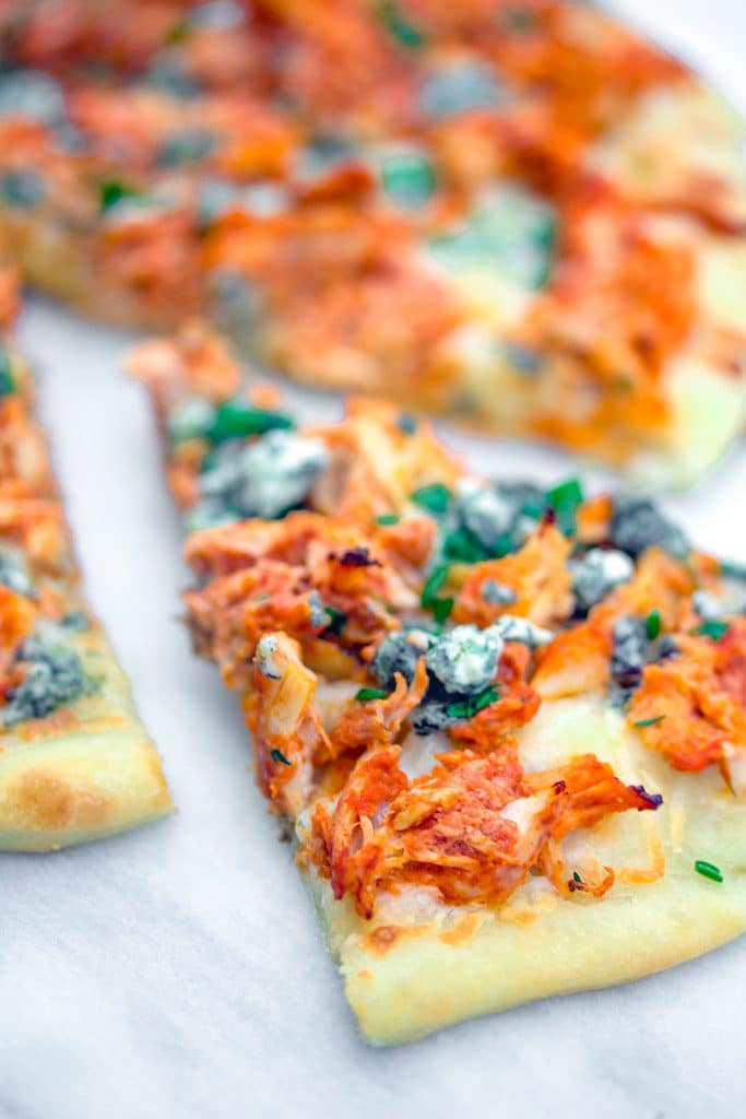 Close-up head-on view of a slice of buffalo chicken pizza on a marble surface