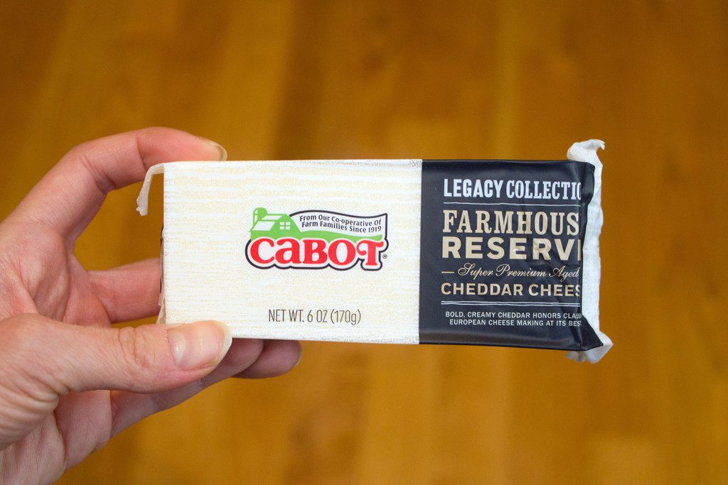 Hand holding a block of Cabot Farmhouse Reserve Cheddar Cheese