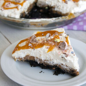 View of a slice of Cadbury Creme Egg Chocolate Cream Pie on a white plate with full pie in background