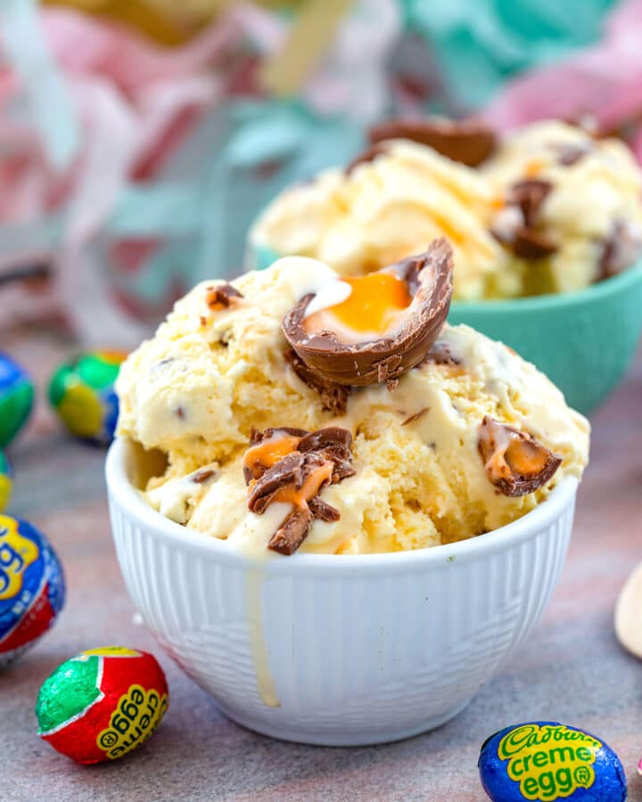 Head-on view of Cadbury Cream Egg ice cream in bowl topped with more candy with wrapped candy all around