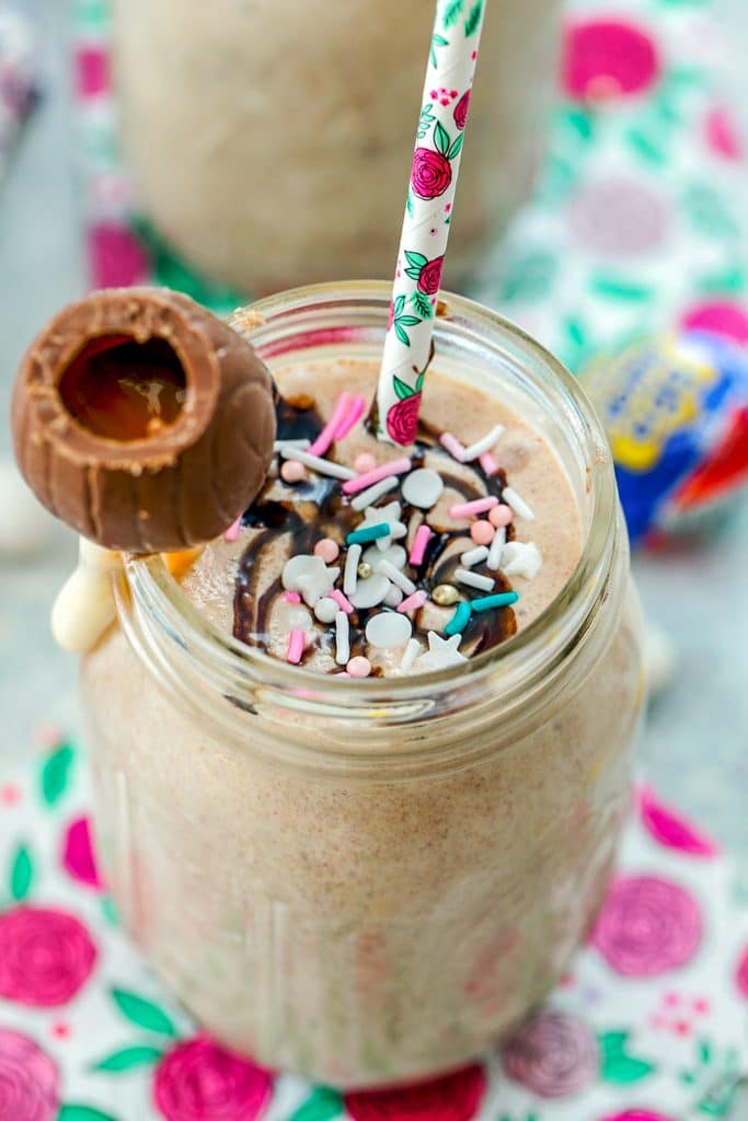 Close-up overhead view of a Cadbury Egg Milkshake with sprinkles, Cadbury Cream Egg garnish, and straw.