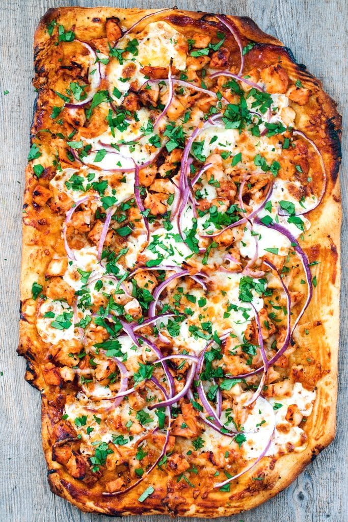 Bird's eye view of BBQ chicken pizza just out of the oven topped with BBQ sauce, chicken, cheese, red onion, and cilantro