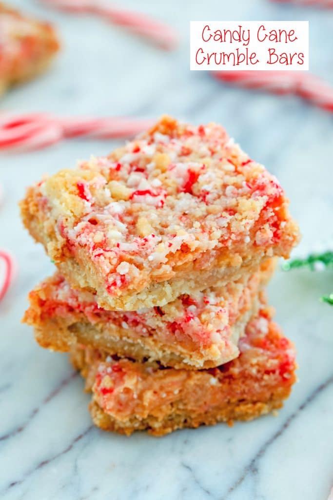 Overhead view of three candy cane crumble bars stacked on top of each other on a marble surface with mini candy canes in the background and recipe title at top