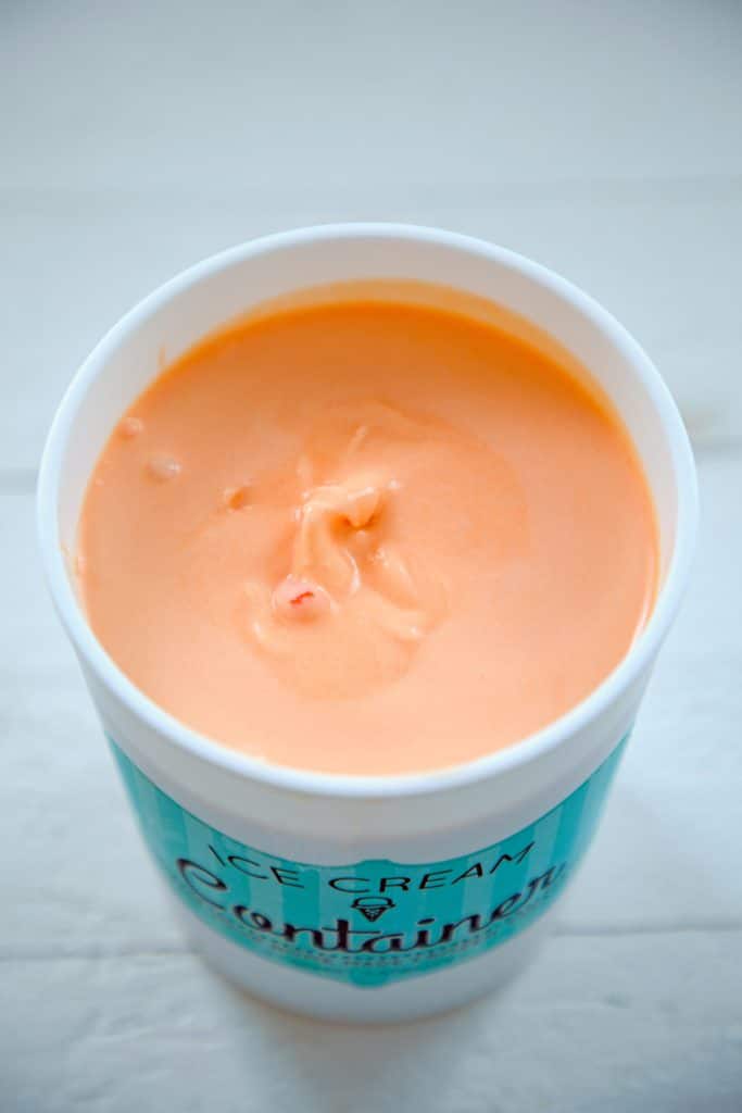 Quart-size ice cream container filled with orange candy corn ice cream before it's fully frozen