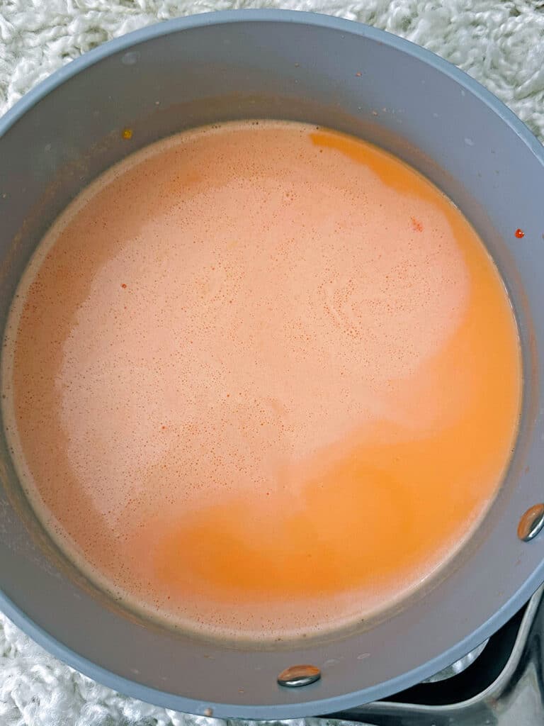 Pale orange milk in saucepan.