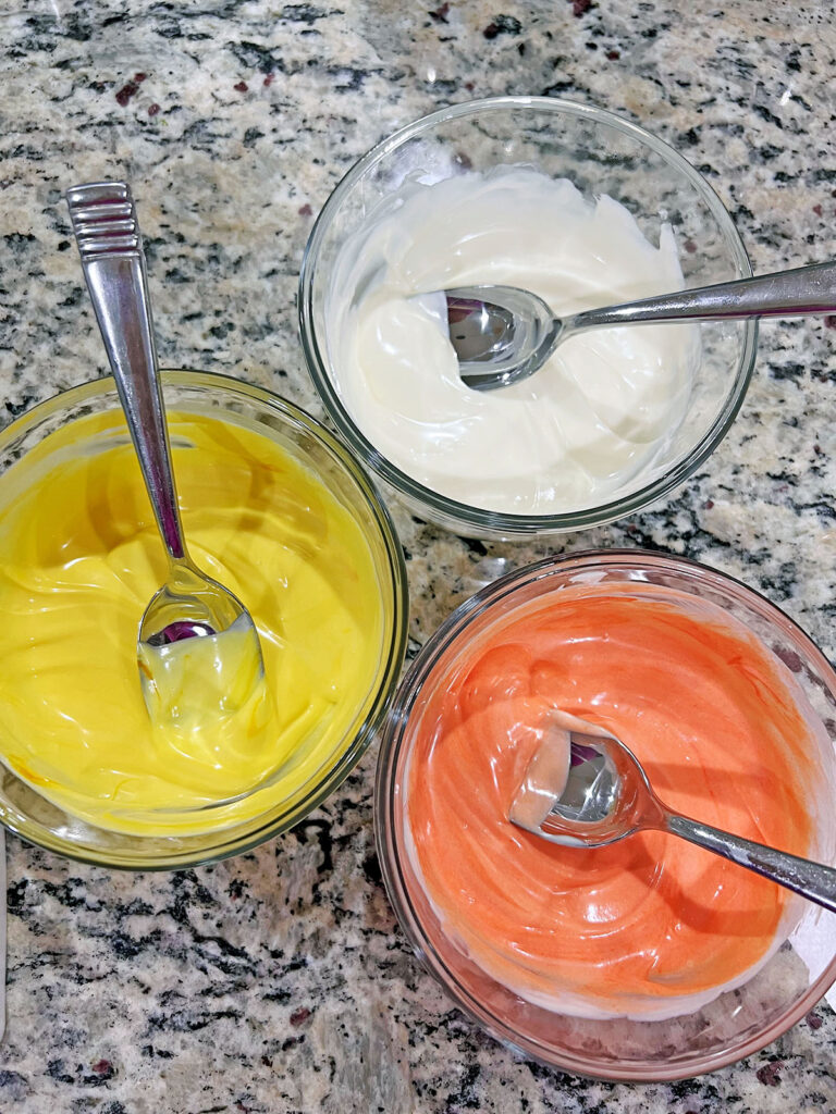 Orange, yellow, and white candy melts melted in bowls