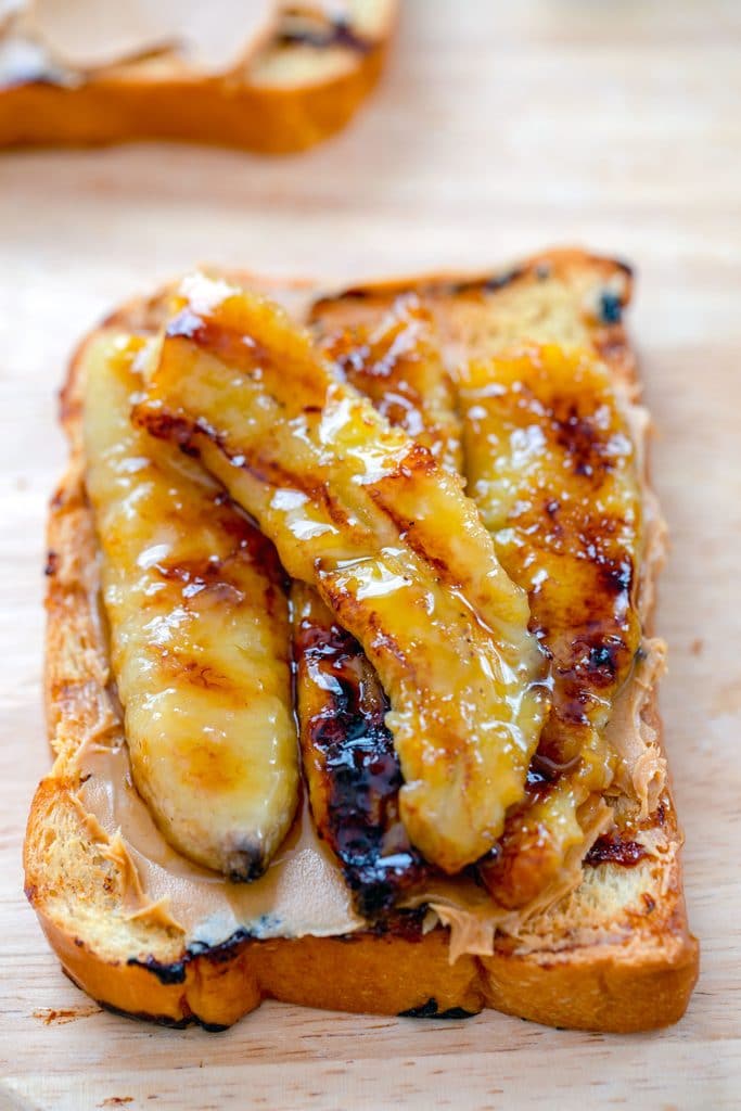 Overhead view of a slice of grilled bread with peanut butter and caramelized bananas on top