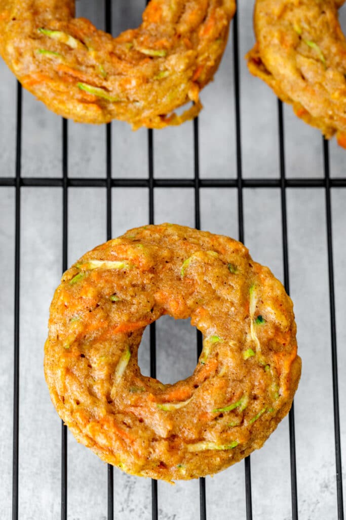 Overhead view of carrot zucchini donuts cooling on metal rack