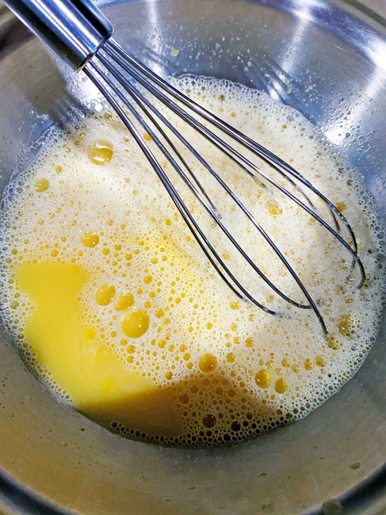 Egg yolks and champagne being whisked together 