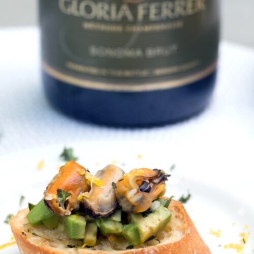 Sparkling Wine Mussel Crostini with Avocado, Grilled Lemon, and Basil -- The perfect party appetizer #GloriousBites | wearenotmartha.com