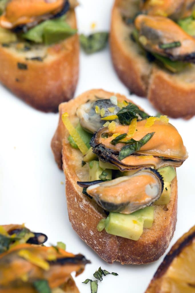 Sparkling Wine Mussel Crostini with Avocado, Grilled Lemon, and Basil -- The perfect party appetizer #GloriousBites | wearenotmartha.com
